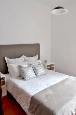 a bed with white sheets and pillows on it at Refúgio Guest House in São Vicente