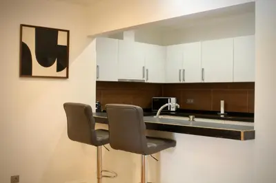 a kitchen with white cabinets and a sink and two chairs at Like Home III - Apartamento com 2 quartos, ideal para famílias e amigos in Funchal