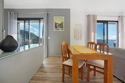 a dining room with a table and chairs and windows at Morning Glory Penthouse in Estreito da Calheta