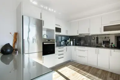 a white kitchen with white cabinets and stainless steel appliances at Morning Glory Penthouse in Estreito da Calheta