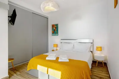 a white bedroom with a large bed with yellow blanket at Morning Glory Penthouse in Estreito da Calheta