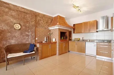 a kitchen with wooden cabinets and a brick wall at Morning Glory 2 Bedroom Apartment in Calheta