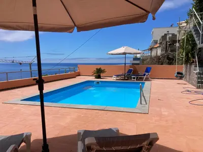 a swimming pool on top of a building with an umbrella at Morning Glory 2 Bedroom Apartment in Calheta