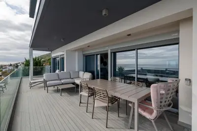 a balcony with a wooden table and chairs at The View residence in Funchal