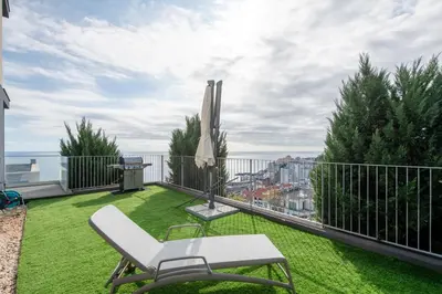 a balcony with green grass and a white chair at The View residence in Funchal