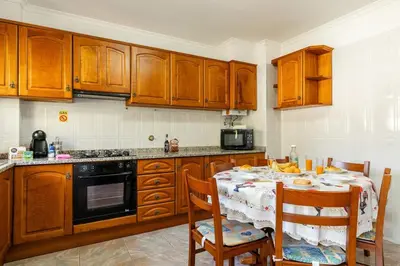 a kitchen with wooden cabinets and a table with chairs at Bela Vale Nº4 in Ribeira Brava