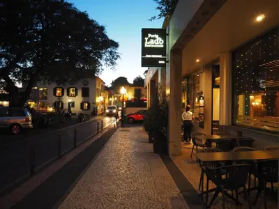 an empty street at night with tables and chairs at Imperatriz Madeira Apartment in Funchal