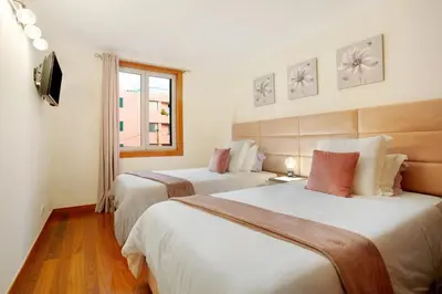 two beds in a hotel room with a window at Imperatriz Madeira Apartment in Funchal