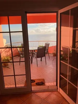 an open door to a balcony with a table and chairs at Casa Rosa in Ponta do Sol