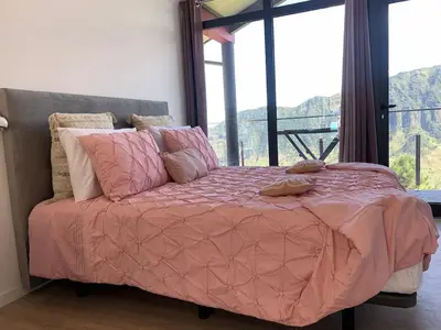 a bed with a pink comforter in a room with a window at Ginjas Mountain Houses in São Vicente