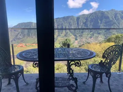 a table and chairs on a balcony with a view of mountains at Ginjas Mountain Houses in São Vicente