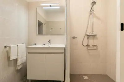 a bathroom with a sink and a shower with a mirror at Sunset House in Calheta