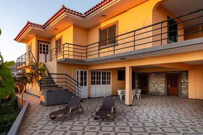 a house with chairs and a balcony on a patio at Sunset House in Calheta