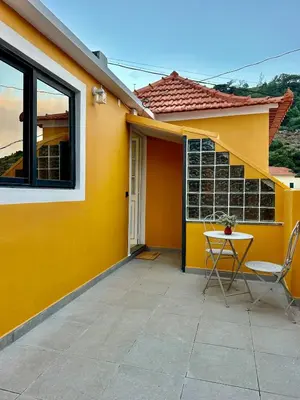 a yellow house with a table and chairs on a patio at Casa do Perestrelo - Guest House in Machico