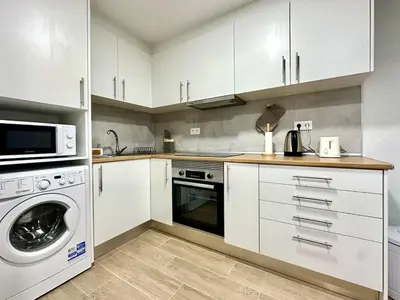 a kitchen with white cabinets and a washer and dryer at Casa do Perestrelo - Guest House in Machico