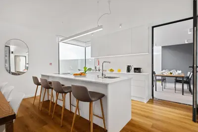 a kitchen with white cabinets and a large island with bar stools at Porto Moniz Atlantic View in Porto Moniz