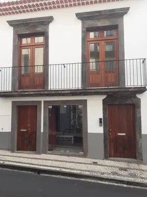 a white building with wooden doors and a balcony at Ferreiros 184 in Funchal