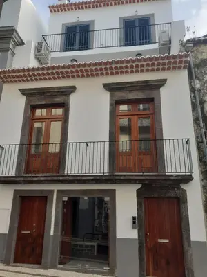 a white house with wooden doors and a balcony at Ferreiros 184 in Funchal