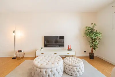 a living room with two white stools and a tv at Suite Q - Supermarket - Pool - AC - Private Parking Spot in Funchal