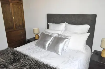 a bed with white sheets and silver pillows at Quinta O Refúgio in São Vicente