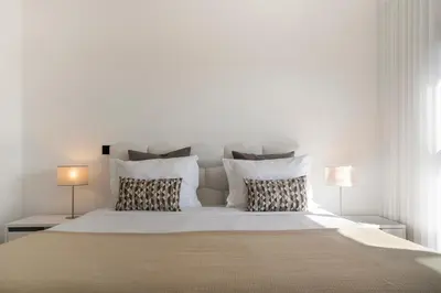 a white bedroom with a large bed with two lamps at São Lucas II by An Island Apart in Funchal