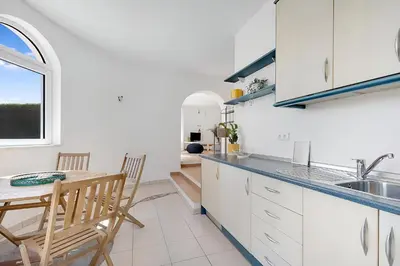 a kitchen with white cabinets and a table and a sink at Arrifana Ocean View Villa in Aljezur