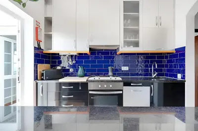 a kitchen with white cabinets and blue tiles at Arrifana Ocean View Villa in Aljezur