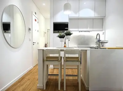 a white kitchen with a sink and two chairs at a counter at CA Tanoeiros 1 in Funchal
