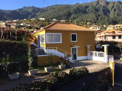 a small yellow house with mountains in the background at Quinta da Colina in São Vicente