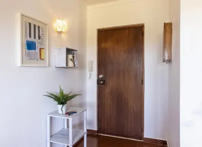 a hallway with a wooden door and a plant on a shelf at Apartamento Branco Beliche in Sagres
