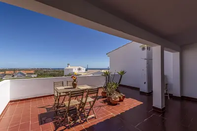 a patio with a table and chairs on a balcony at Apartamento Branco Beliche in Sagres