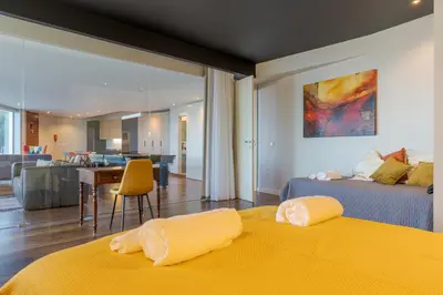 a bedroom with two beds and a living room at A Porta das Neves in Funchal