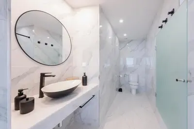 a white bathroom with a sink and a mirror at A Porta das Neves in Funchal