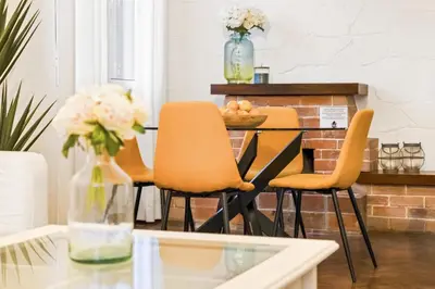 a dining room with orange chairs and a glass table at Casa do Santo by Homie in Santo da Serra
