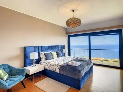 a bedroom with a blue bed and a large window at Rising Sun Villa in Gaula