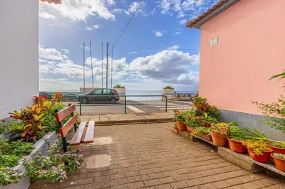a bench sitting next to a building with flowers at Ferreira's Retreat in Ponta do Sol