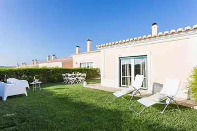 a yard with chairs and tables and a building at Villas T3 com Jardim Vila Sagres in Sagres