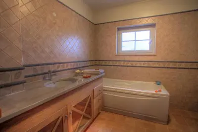 a bathroom with a sink and a tub and a window at Villas T3 com Jardim Vila Sagres in Sagres