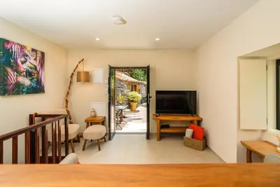 a living room with a television and a table at Casas da Terça - modern comfort in traditional houses set within 300sqm of private gardens to explore in Tábua