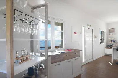 a white kitchen with glasses hanging from the wall at Ozeanica Heights by LovelyStay in Gaula