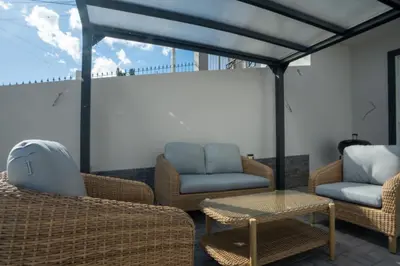 a patio with wicker chairs and a table and a couch at Ozeanica Heights by LovelyStay in Gaula