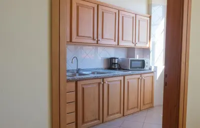 a kitchen with wooden cabinets and a sink and a microwave at Apartments Madeira Santa Maria in Funchal