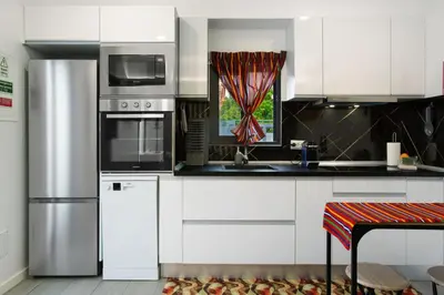 a kitchen with white cabinets and stainless steel appliances at Litlle Zen House in Santana