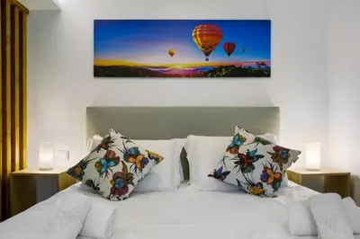 a bed with two pillows and a picture of hot air balloons at Litlle Zen House in Santana