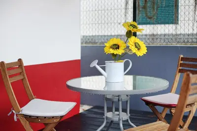 a table with a vase with yellow flowers on it at Litlle Zen House in Santana