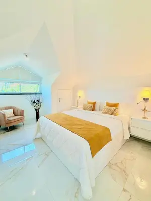 a white bedroom with a large bed and a couch at Refúgio do Vale Verde in Ponta do Sol