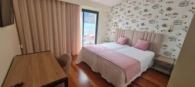 a bedroom with a bed with pink pillows and a table at Casa Linda Baía in Porto da Cruz