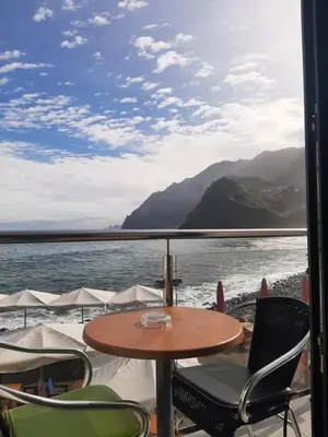 a table and chairs on a balcony with a view of the water at Casa Linda Baía in Porto da Cruz