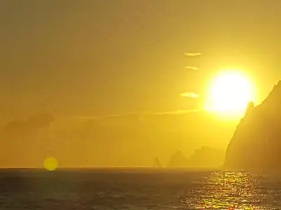 a sunset over the ocean with the sun in the sky at Casa Linda Baía in Porto da Cruz