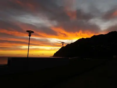a sunset on the beach with a light pole at Casa Linda Baía in Porto da Cruz
